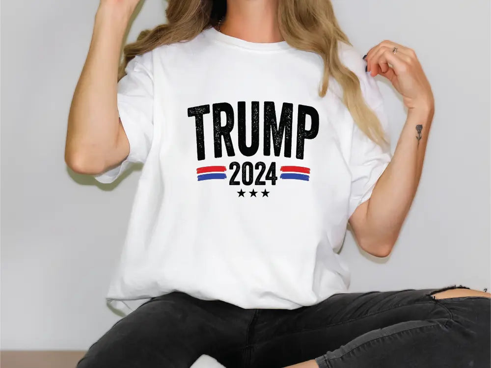 a woman sitting on a table wearing a trump t - shirt