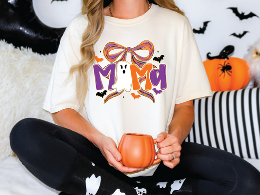 A woman wearing a white t-shirt with a Halloween-themed design is sitting on a couch, holding a pumpkin-shaped mug.
