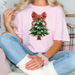 a woman sitting on a couch wearing a pink shirt with a christmas tree on it