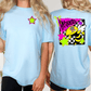 two women wearing light blue t-shirts with colorful designs on the back.