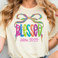 A woman wearing a white t-shirt with a colorful graphic design and text.
