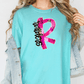 A woman wearing a turquoise t-shirt with a pink and black design on it, and a denim jacket.