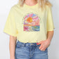 a woman wearing a yellow shirt with a painting on it