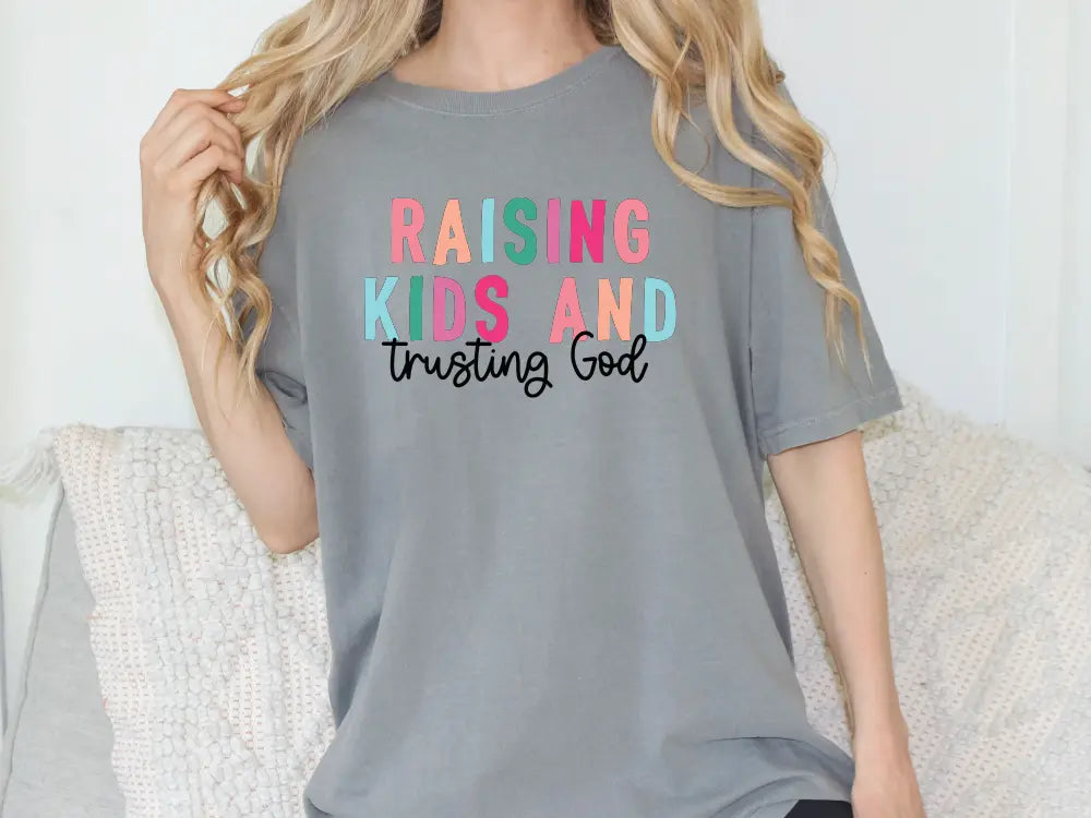 a woman wearing a t - shirt that says raising kids and trying god