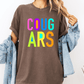 A person wearing a brown t-shirt with the text "COUGARS" in colorful letters, paired with a denim jacket.