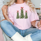 a woman sitting on a couch holding a christmas tree t - shirt