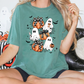 A woman wearing a green t-shirt with a Halloween-themed graphic of ghostly figures and pumpkins.