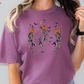 a woman wearing a purple t - shirt with skeletons and pumpkins on it