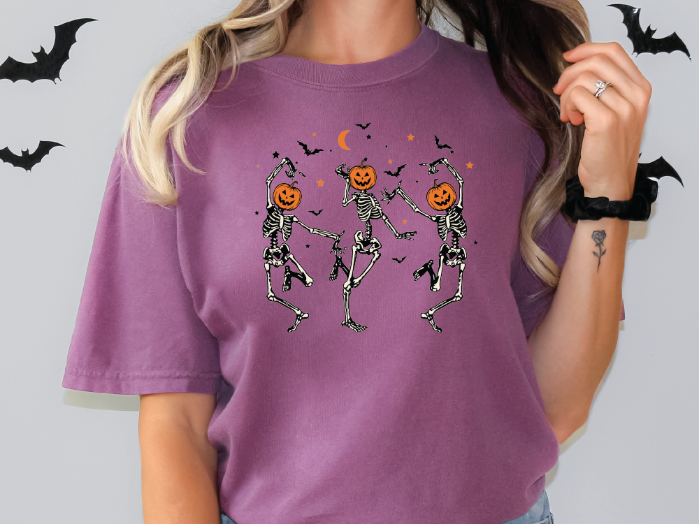 a woman wearing a purple t - shirt with skeletons and pumpkins on it