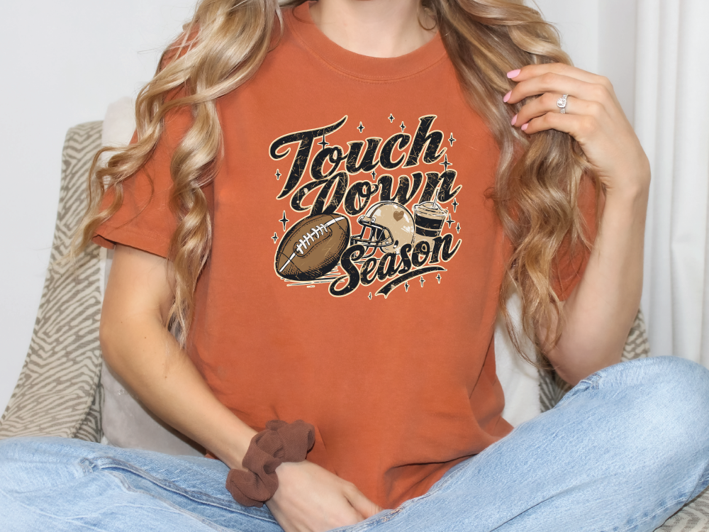 a woman sitting on a couch wearing a t - shirt that says touch down season