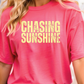 a woman wearing a pink shirt that says chasing sunshine