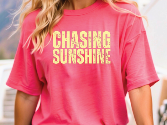 a woman wearing a pink shirt that says chasing sunshine