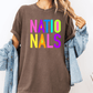 A person wearing a brown t-shirt with the text "NATIO NALS" in colorful letters, paired with a denim jacket.