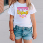 a little girl wearing a white shirt and denim shorts