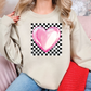 a woman sitting on a couch wearing a sweater with a heart on it