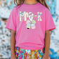 a little girl wearing a pink shirt and colorful shorts