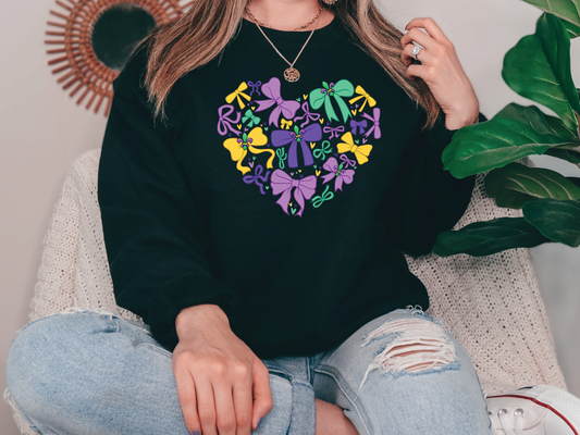 a woman sitting on a chair wearing a black sweatshirt with a heart shaped design