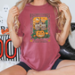 a woman sitting on a bed holding up a halloween t - shirt