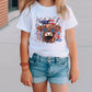 a little girl standing on a sidewalk wearing a shirt with a bull on it