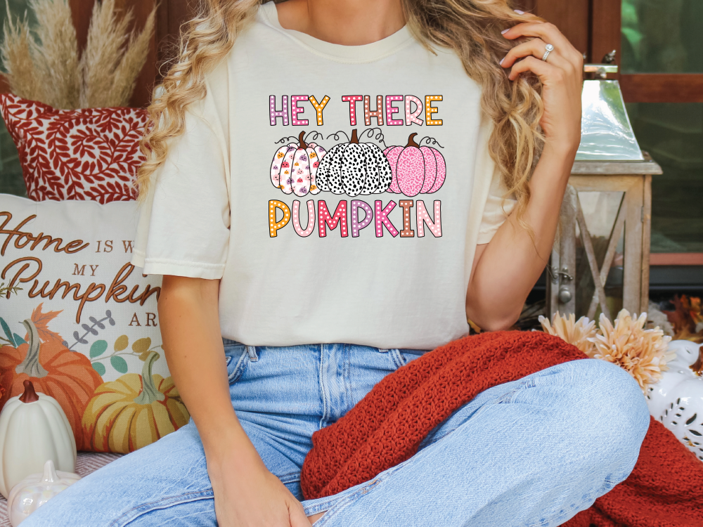 a woman sitting on a couch wearing a t - shirt that says hey there pumpkin