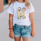 a little girl wearing a white shirt and jean shorts