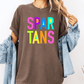 A person wearing a brown t-shirt with the text "SPAR TANS" in colorful letters, along with a denim jacket, stands against a white background.