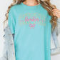 A woman wearing a teal t-shirt with the word "CHEER" printed on it, along with a denim jacket.