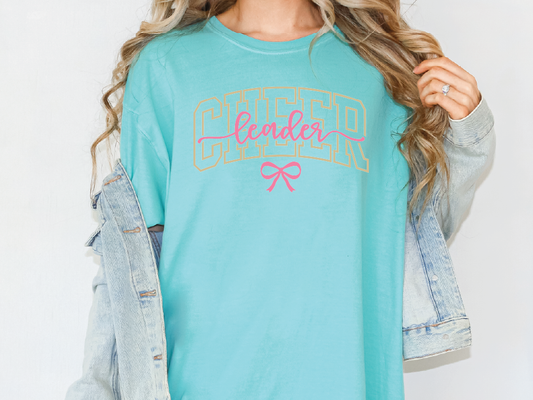 A woman wearing a teal t-shirt with the word "CHEER" printed on it, along with a denim jacket.
