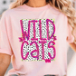 A woman wearing a pink t-shirt with the text "WILD CATS" printed on it.
