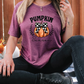 a woman sitting on the ground with a pumpkin on her shirt