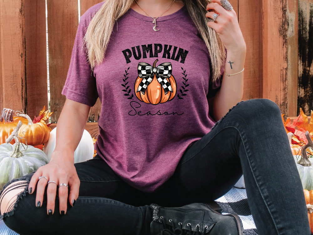 a woman sitting on the ground with a pumpkin on her shirt