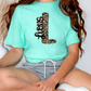 A person wearing a mint green t-shirt with a leopard print design and gray shorts is sitting on the floor.
