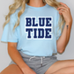 a woman sitting on a table wearing a blue tide t - shirt