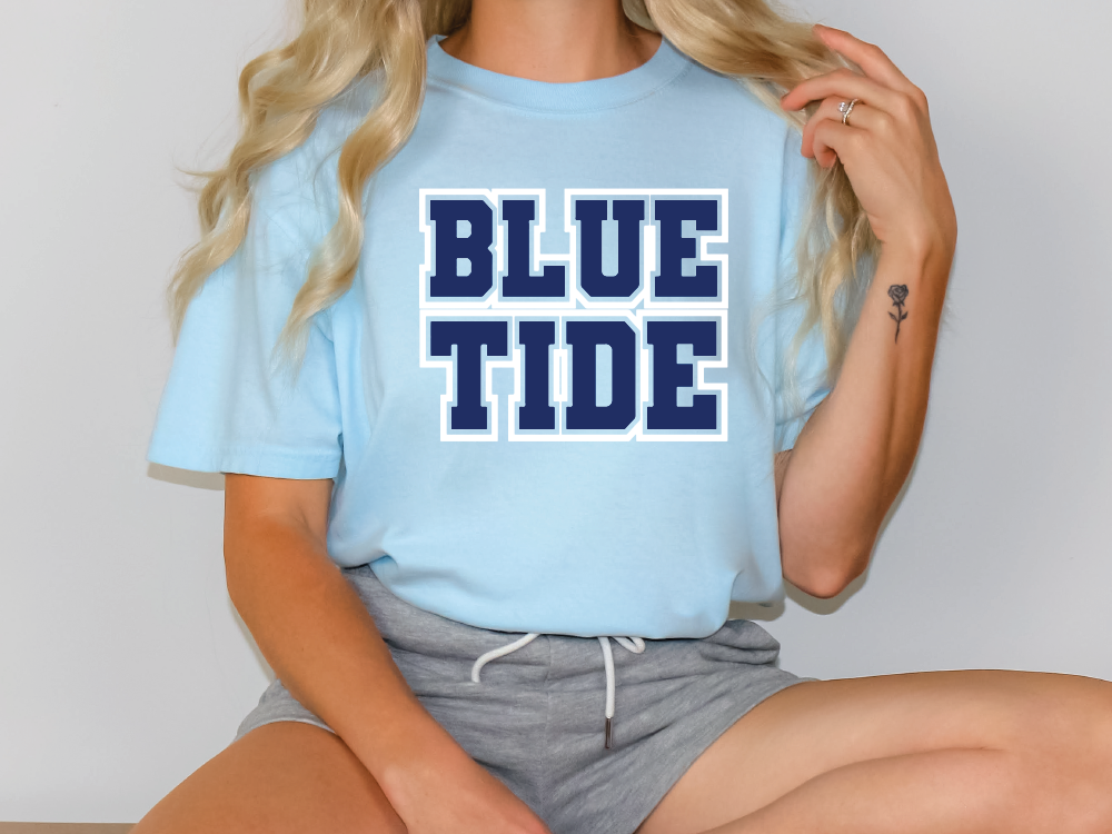 a woman sitting on a table wearing a blue tide t - shirt