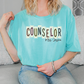 A woman wearing a light blue t-shirt with the text "COUSELLOR" and "Mrs. Jessica" printed on it, sitting on a couch.