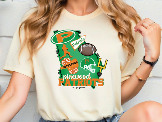 A person wearing a white t-shirt with a graphic design featuring various sports-related elements, including a football, cheerleaders, and the text "Patriots" and "Pinewood Patriots".