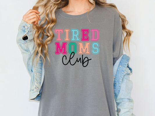 a woman wearing a grey tired moms club shirt