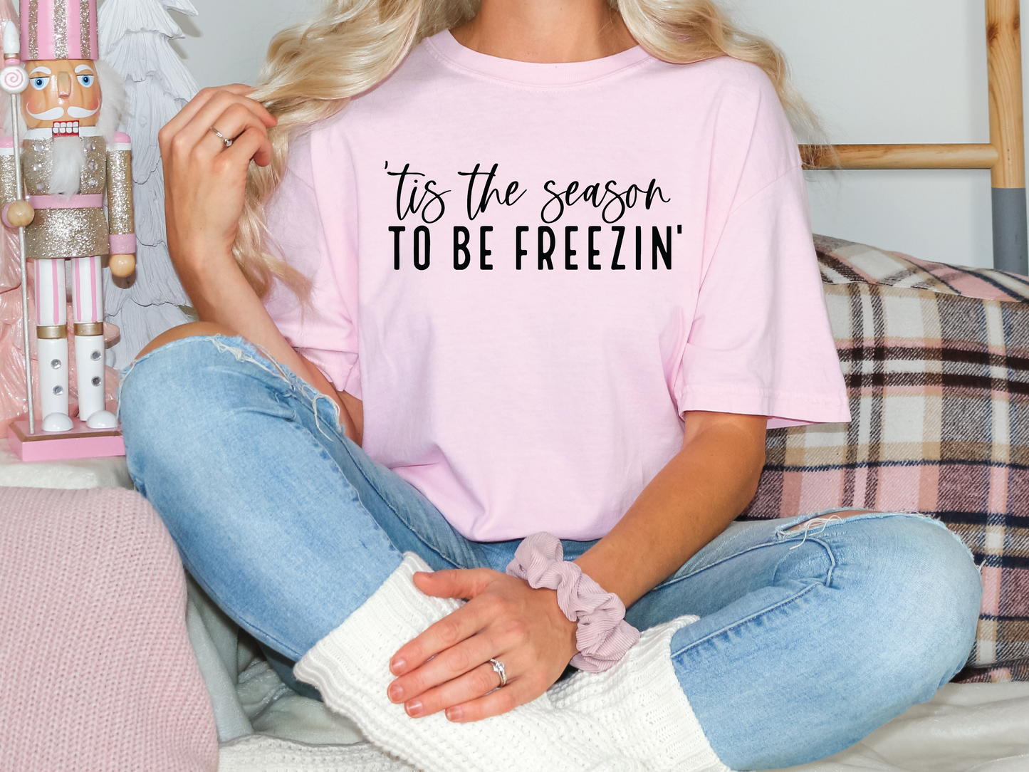 a woman sitting on a couch wearing a pink shirt that says tis the season to