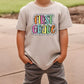 a young boy wearing a t - shirt that says first grade