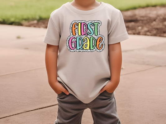 a young boy wearing a t - shirt that says first grade