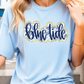 A woman wearing a light blue t-shirt with the word "Blue Tide" printed on it.