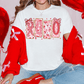 A woman wearing a white t-shirt with the word "LOVE" printed on it, surrounded by red balloons and a red sweater.