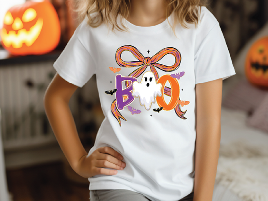 A person wearing a white t-shirt with a graphic design featuring a ghost and the word "BOO" in a playful, festive style.