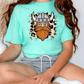 A person wearing a turquoise t-shirt with a graphic of a Viking helmet and beard, sitting cross-legged on the floor.