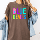 A person wearing a brown t-shirt with the text "BLUE DEVILS" printed on it, along with a denim jacket.