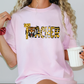 A woman wearing a pink t-shirt with the word "Teacher" printed on it, holding a white mug in her hand.