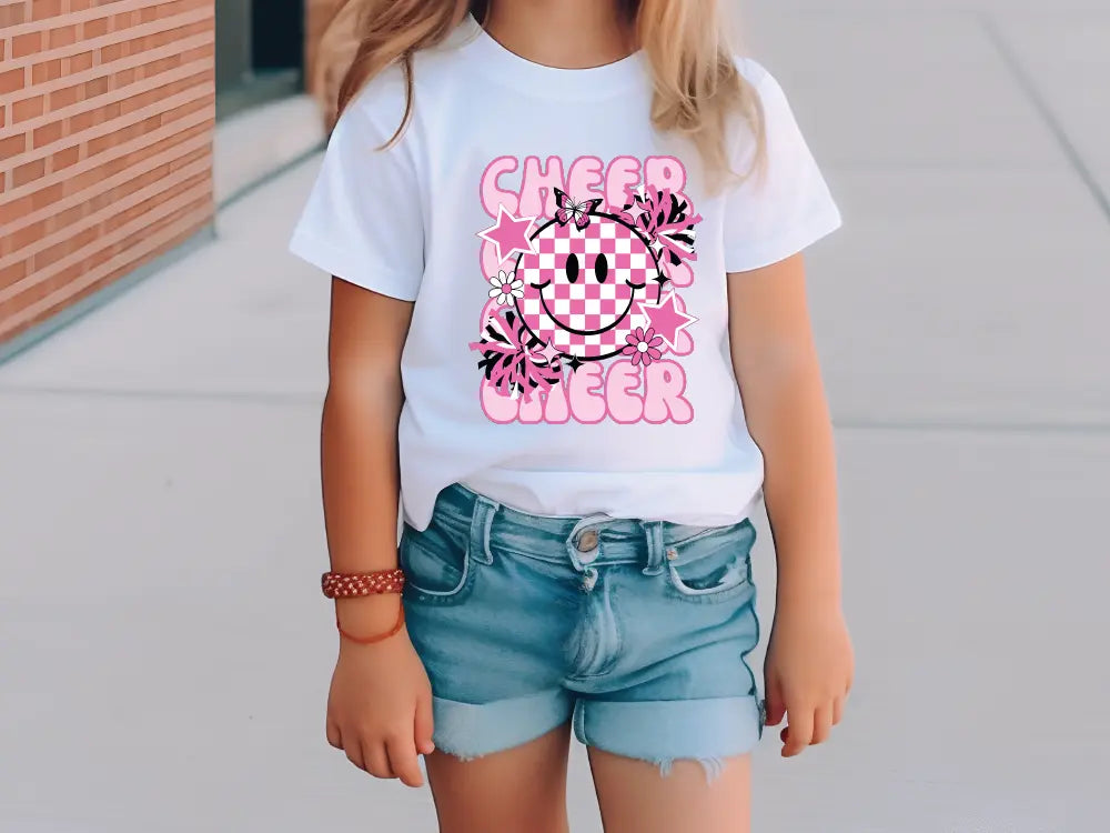 a little girl standing on a sidewalk wearing a t - shirt that says cheer cheer