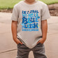 a young boy standing on a sidewalk wearing a t - shirt