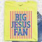 A yellow t-shirt with the text "BIG JESUS FAN" printed on it, along with vertical stripes in pink and blue.