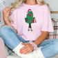 a woman sitting on a couch wearing a pink shirt with a christmas tree on it